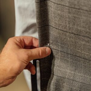 A hand adjusting a button on a tailored suit jacket, focusing on detail.