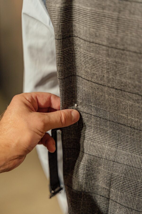 A hand adjusting a button on a tailored suit jacket, focusing on detail.